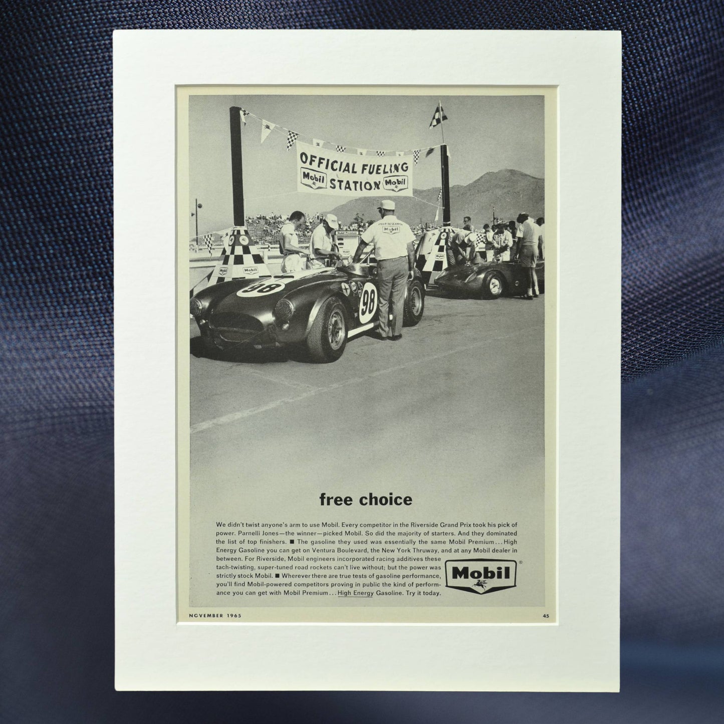 1965 Mobil vintage print ad featuring Shelby Cobra No. 98 at the Riverside Grand Prix fueling station. Driven by Ken Miles, Bob Bondurant, and Parnelli Jones.