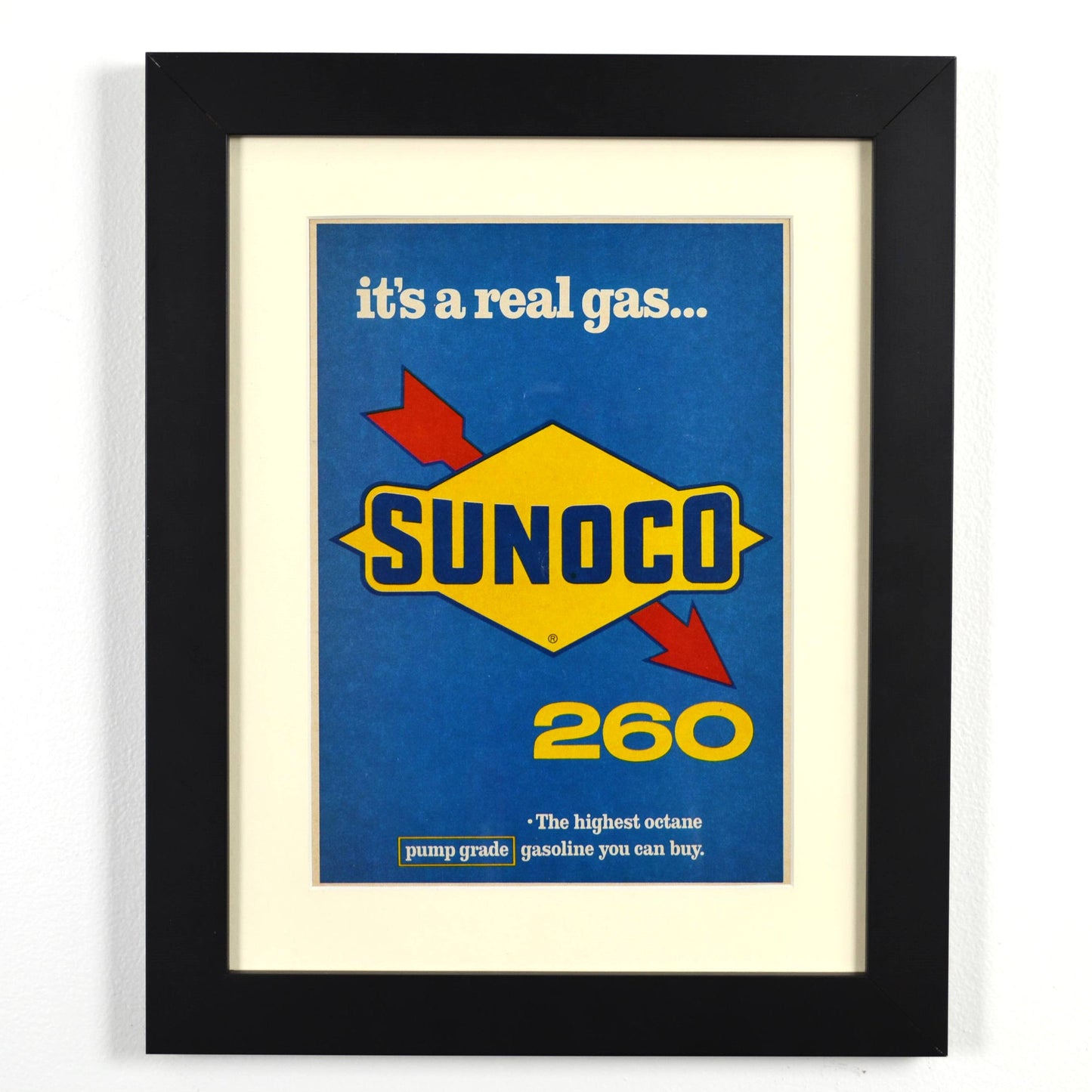 Framed vintage 1966 Sunoco 260 print ad featuring the bold blue and yellow Sunoco logo and the tagline ‘It’s a real gas...’ Professionally dry mounted and displayed in a 10x13 matte black frame with white matting