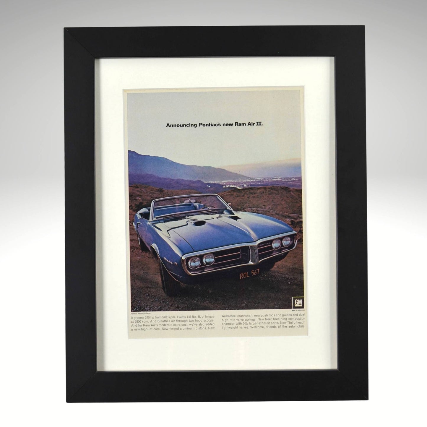 Framed 1967 Pontiac Firebird Ram Air II convertible ad – vintage muscle car print with scenic background and GM performance theme.