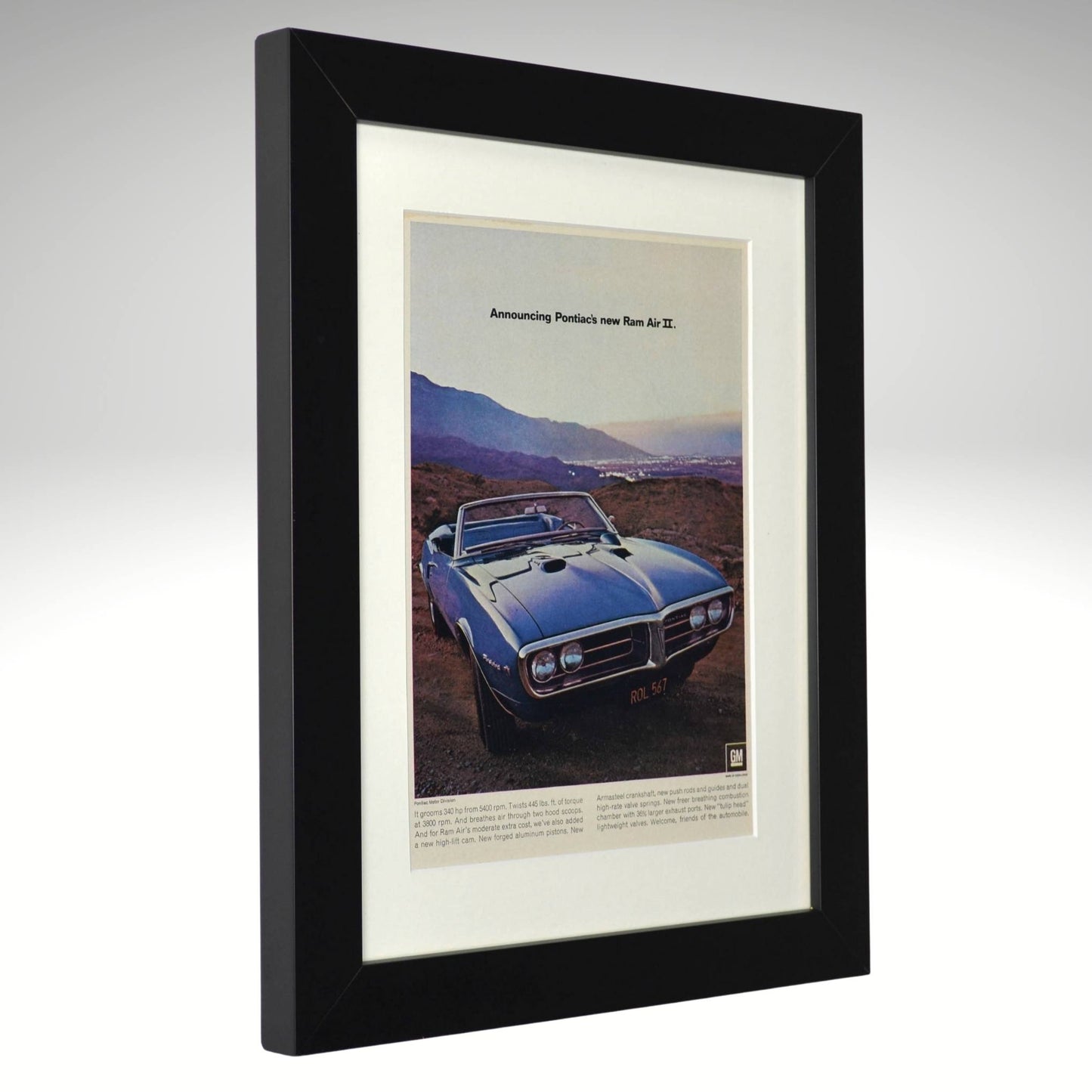 Framed advertisement of a blue 1967 Pontiac Firebird Ram air II on a mountain background