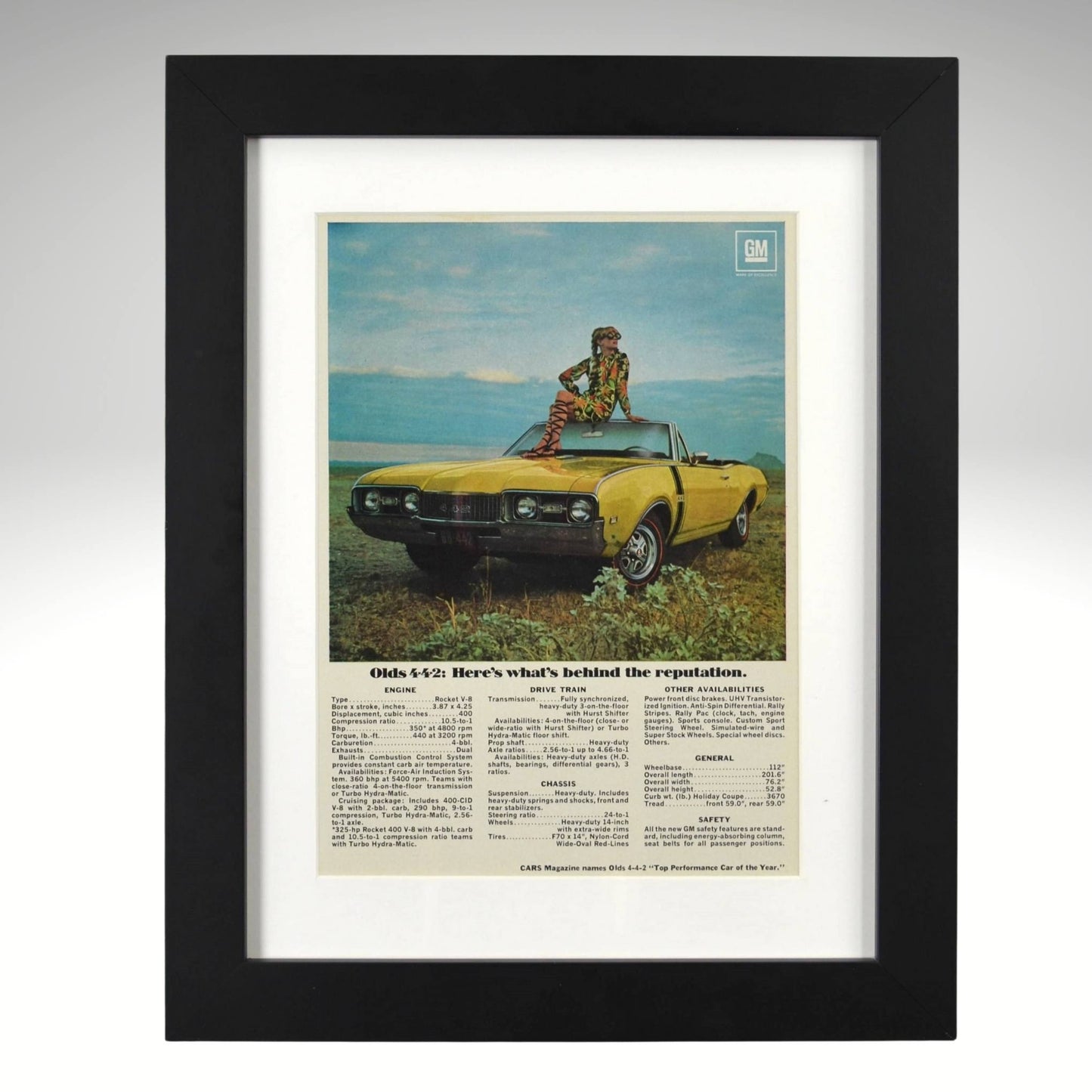 Framed 1968 Oldsmobile 442 convertible print ad – yellow 442 with woman sitting on hood in scenic field.