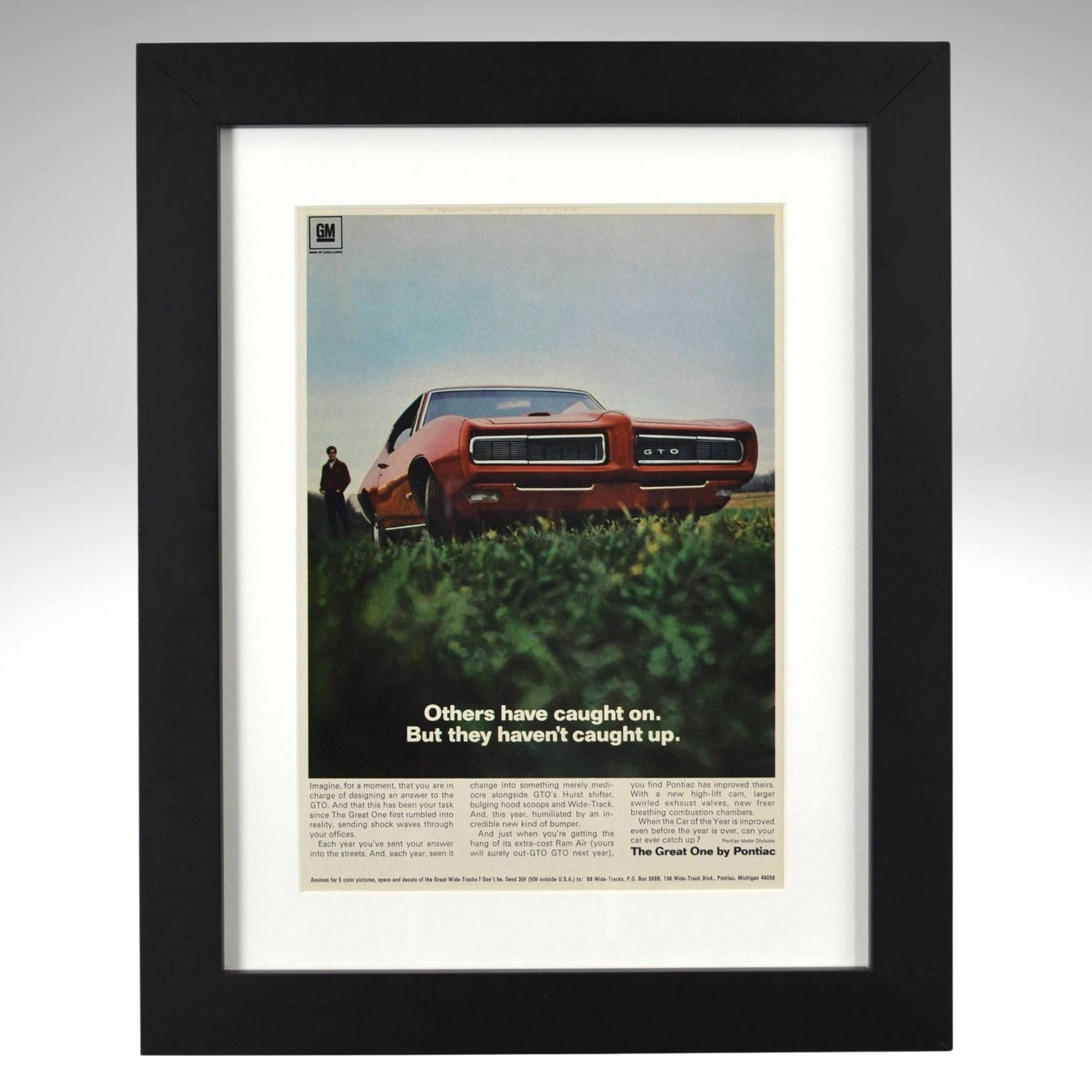 Framed 1968 Pontiac GTO print ad – vintage muscle car art featuring red GTO with hidden headlights and bold low-angle view.