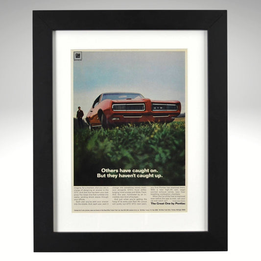 Framed 1968 Pontiac GTO print ad – vintage muscle car art featuring red GTO with hidden headlights and bold low-angle view.