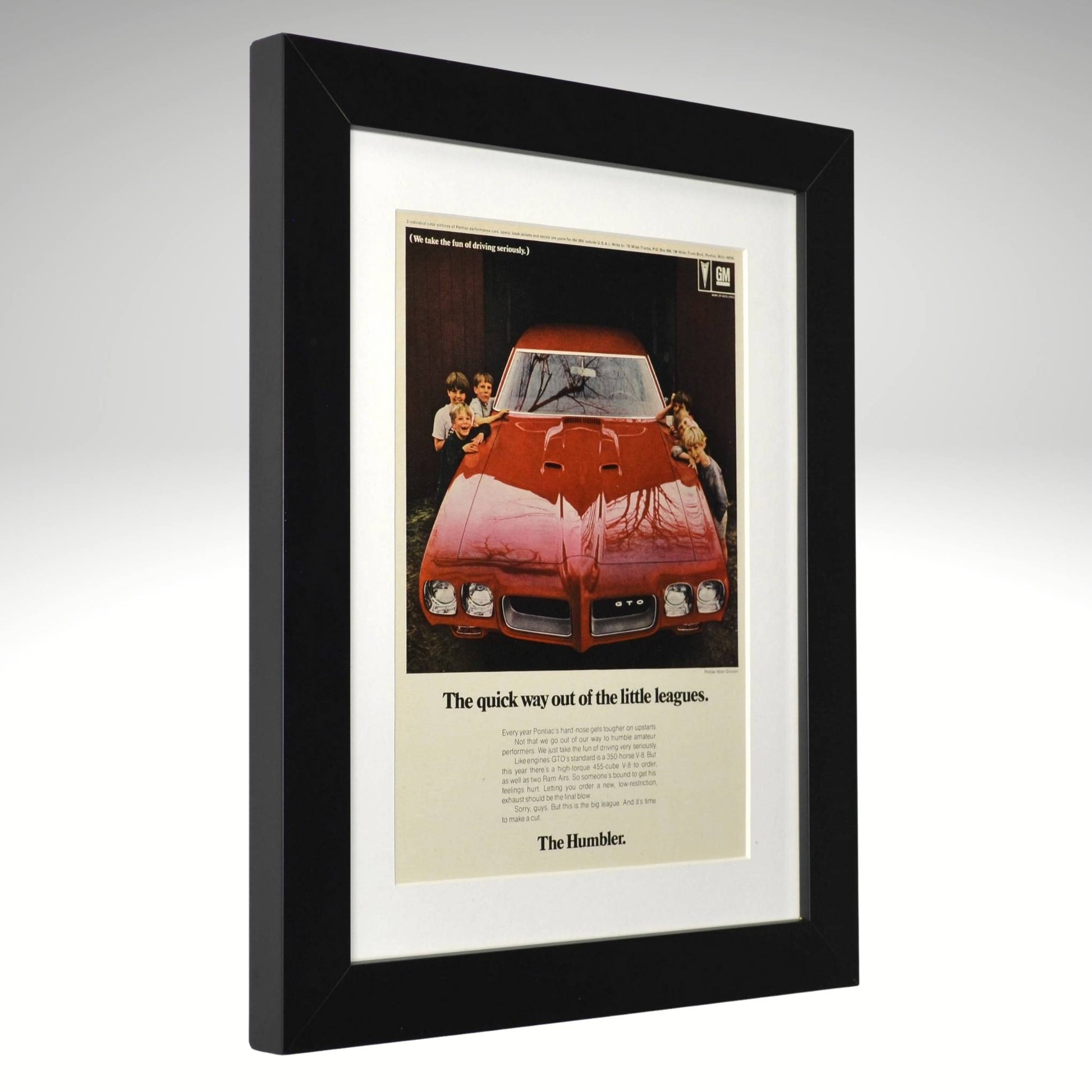 Framed 1970 Pontiac GTO Humbler ad – vintage print showing red GTO in garage with kids, tagline “The quick way out of the little leagues.” side view