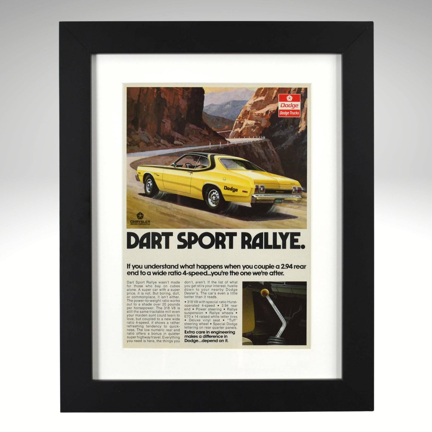 Framed 1973 Dodge Dart Sport Rallye vintage print ad featuring a yellow Dart on a mountain road with headline “Dart Sport Rallye.” Displayed in a matte black frame with white mat — perfect Mopar wall art for collectors and enthusiasts.