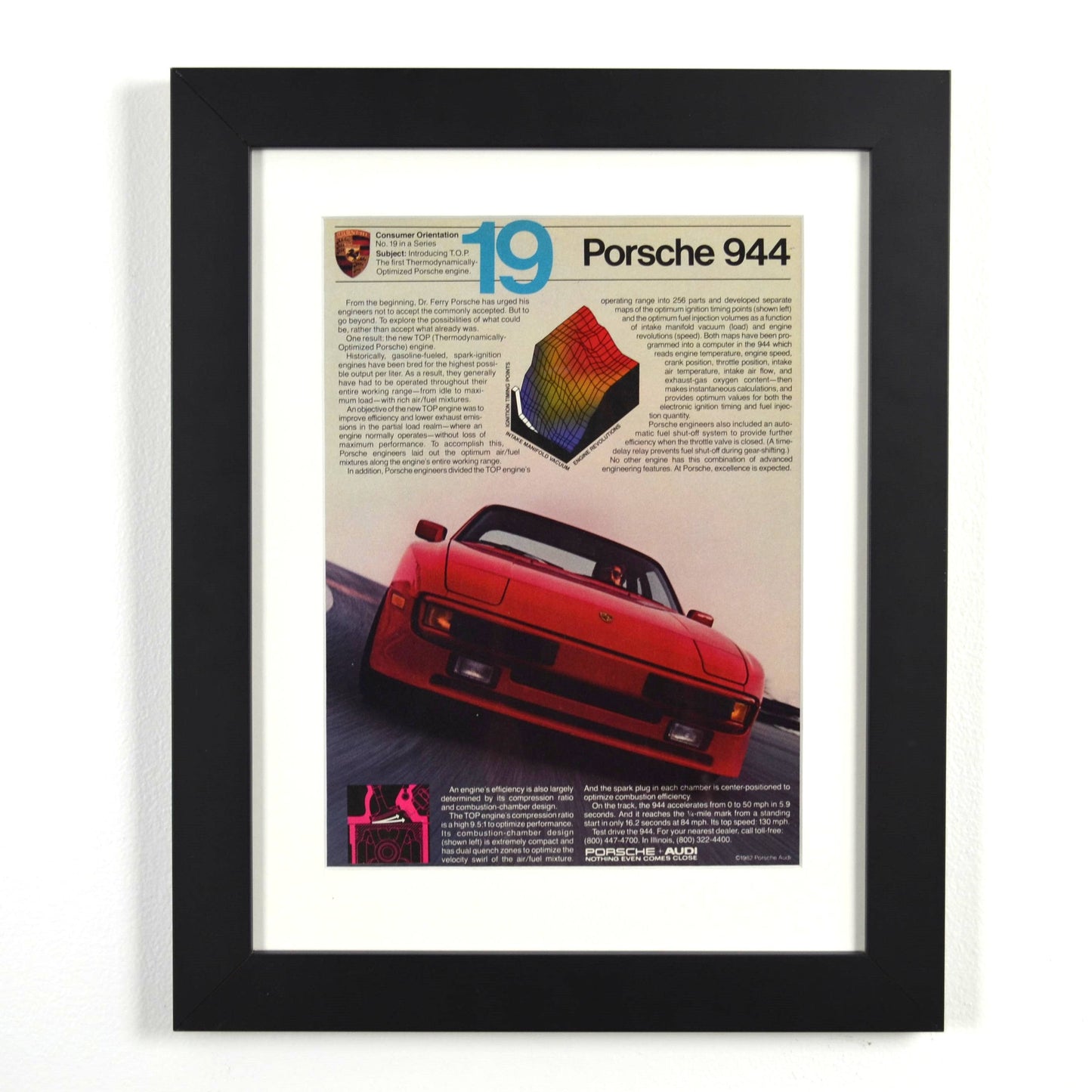 Framed vintage 1982 Porsche 944 magazine ad featuring red 944 in motion with technical graphics, dry-mounted and matted in black frame for wall display.
