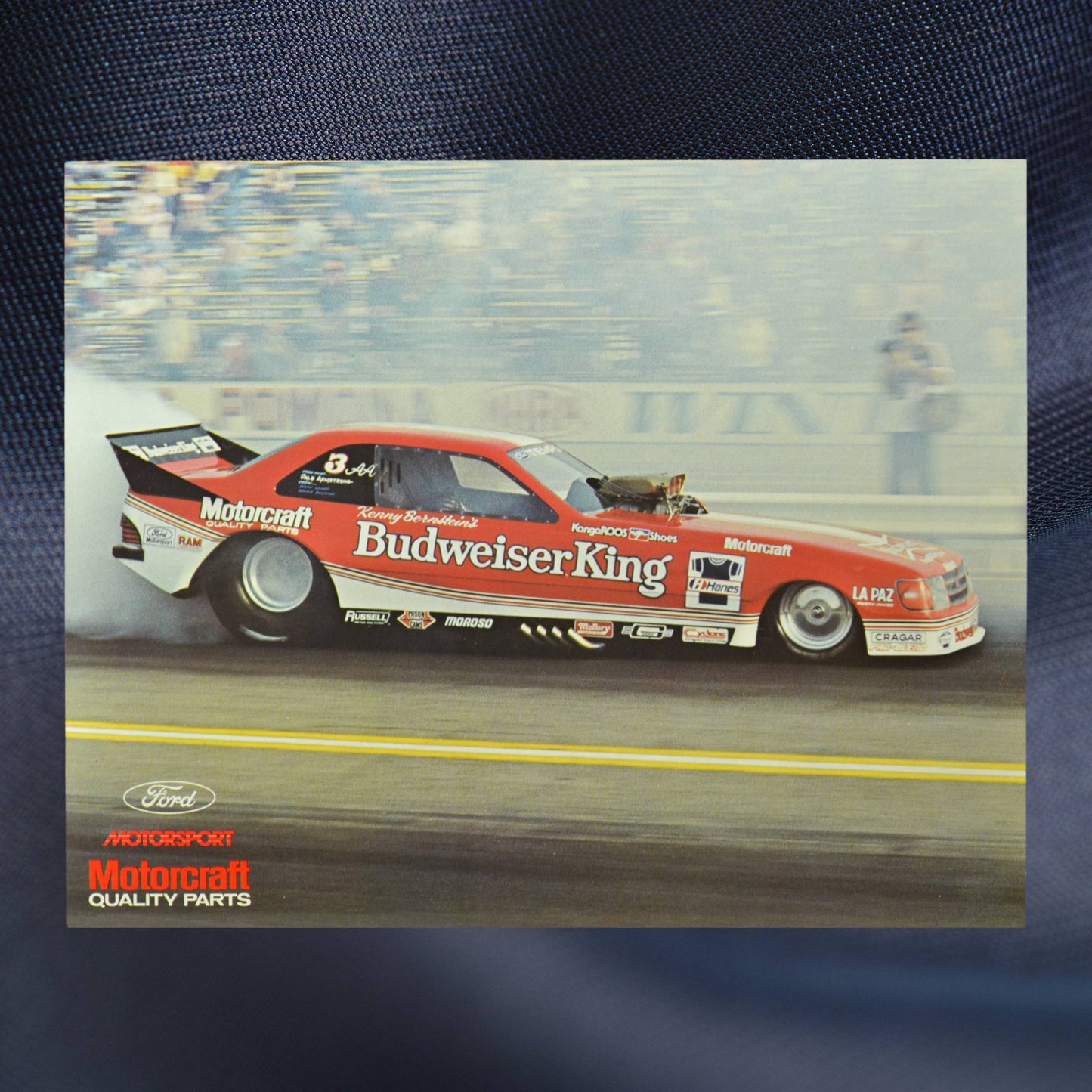 1984 NHRA hero card showing Kenny Bernsteinās Budweiser King Funny Car in action, leaving a trail of smoke as it thunders down the dragstrip
