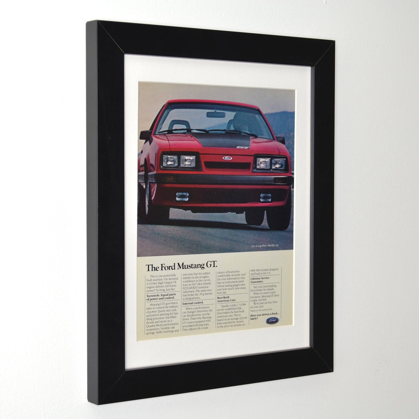 Framed side view of 1985 Ford Mustang GT vintage print ad featuring the iconic Foxbody Mustang in red. Classic muscle car advertisement, perfect for garage decor and Mustang collectors.
