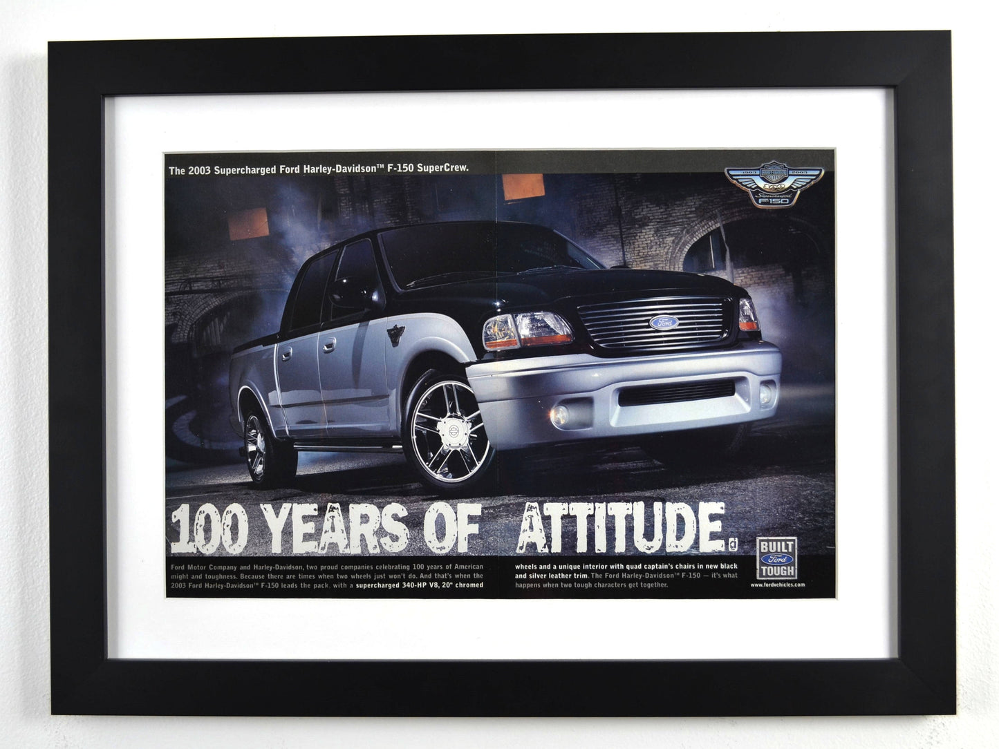 Framed vintage 2003 Ford Harley-Davidson F-150 print ad featuring a black and silver SuperCrew pickup with Harley-Davidson badging. Professionally dry mounted and displayed in a 15x20 matte black frame with white matting.