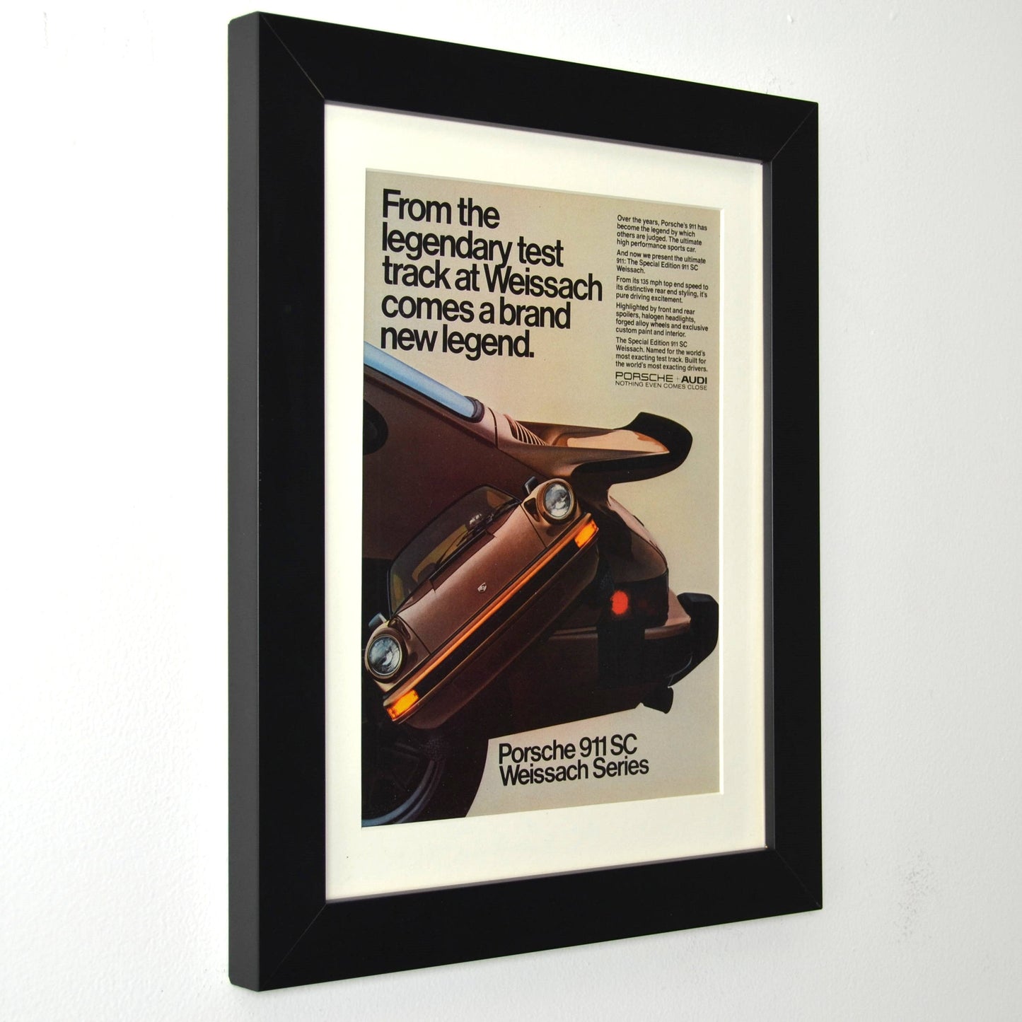 Framed vintage Porsche 911 SC Weissach Series print ad, featuring the limited-edition sports car. Professionally dry mounted and displayed in a 10x13 matte black frame with white matting, ready for wall display side view