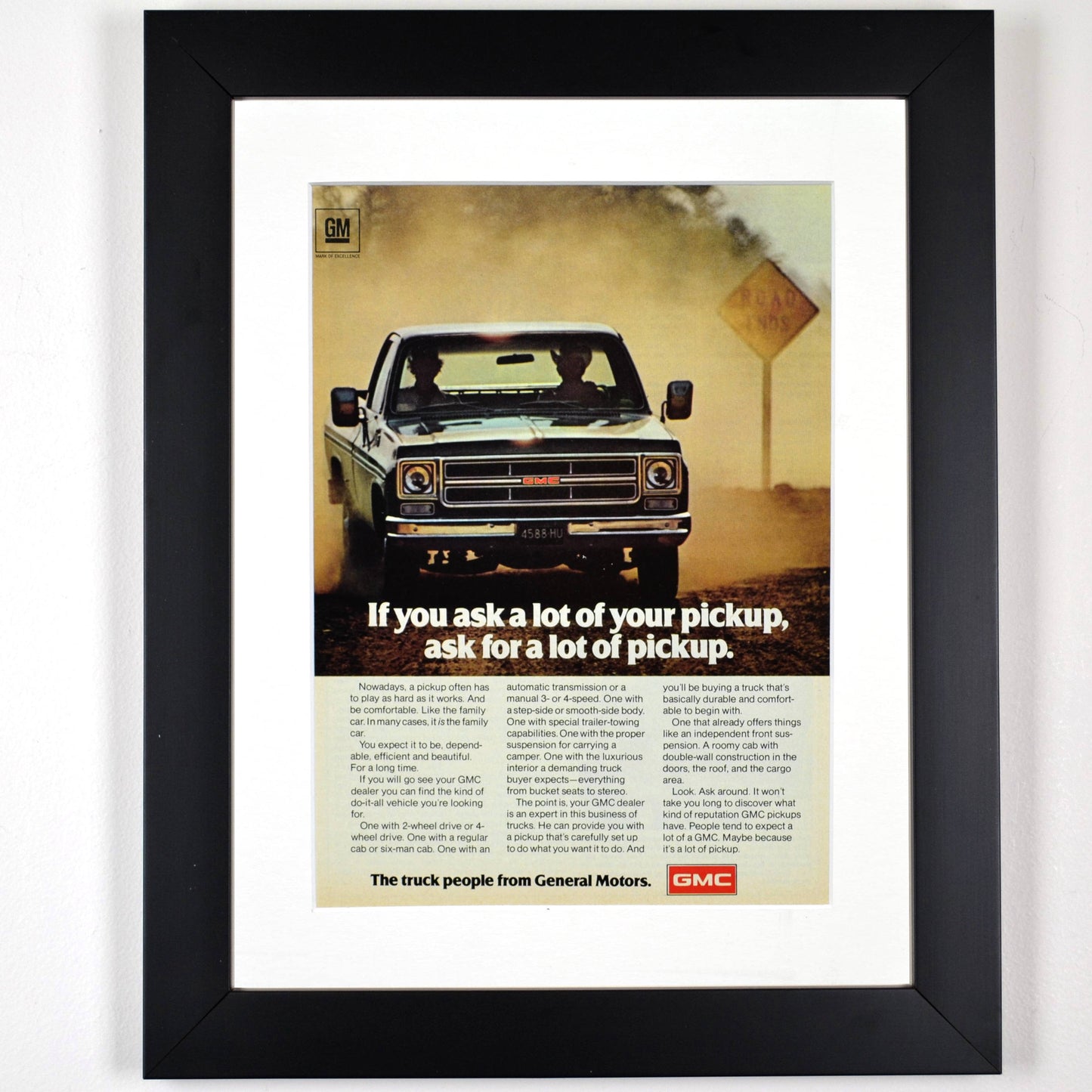 Framed 1975 GMC truck ad featuring a squarebody pickup driving through dust with bold typography and vintage styling.