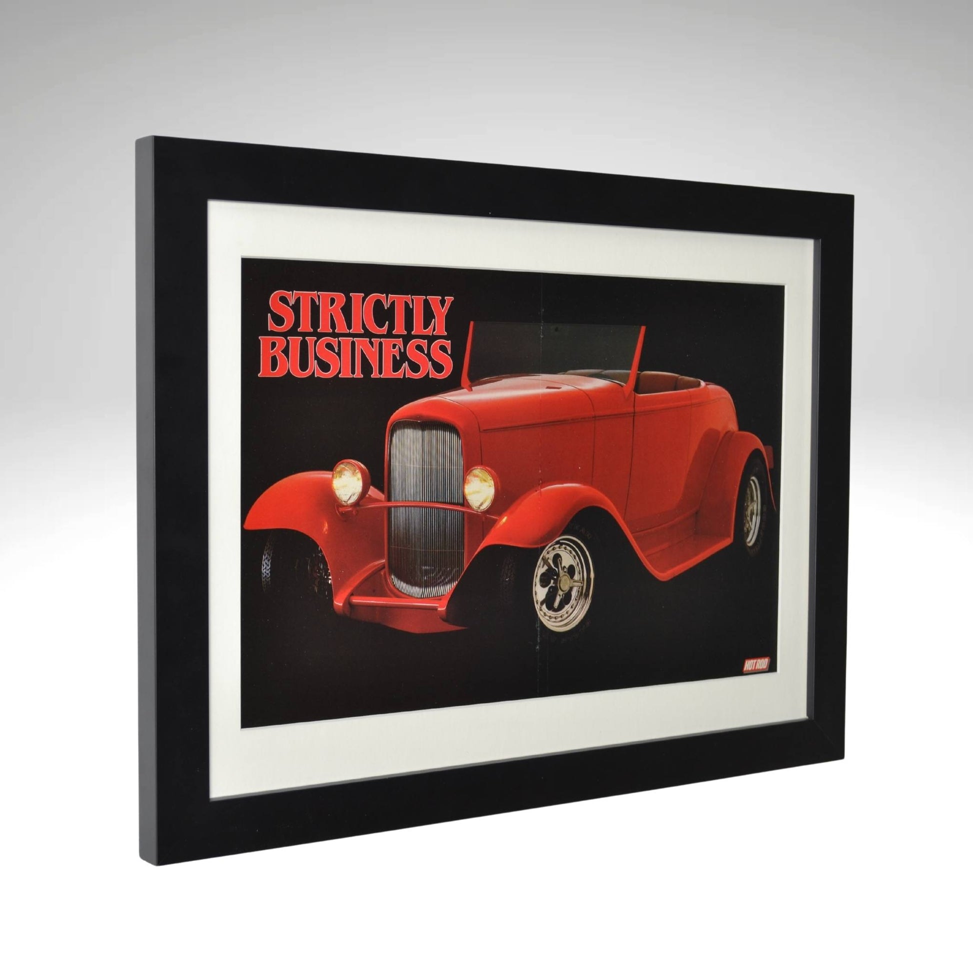 Side view of Framed poster of a 1932 Ford Hot Rod titled "Strictly Business," from a Hot Rod Magazine centerfold, featuring a bold red car in a sleek black frame.