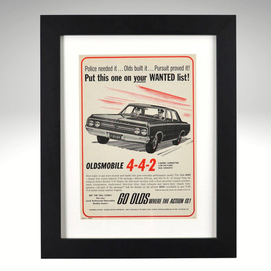 Framed 1964 Oldsmobile 442 print ad – black sedan with “Put this one on your WANTED list” headline, vintage muscle artwork.

