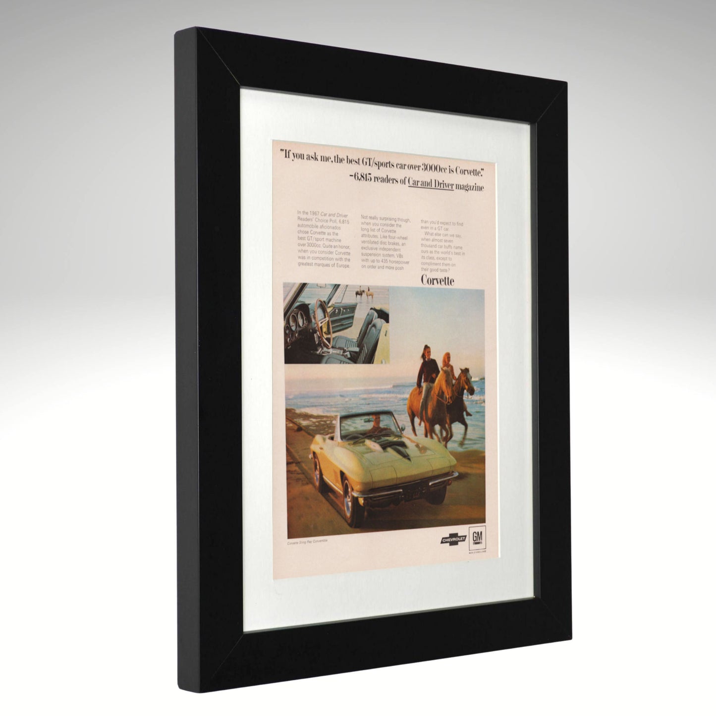 A framed vintage Chevrolet Corvette advertisement print with a black frame and white mat, shown at a slight angle against a neutral gray background.