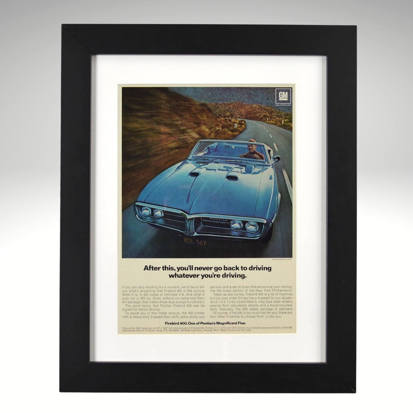 Framed 1967 Pontiac Firebird 400 convertible print ad – vintage GM muscle car wall art with blue Firebird driving on a mountain road.