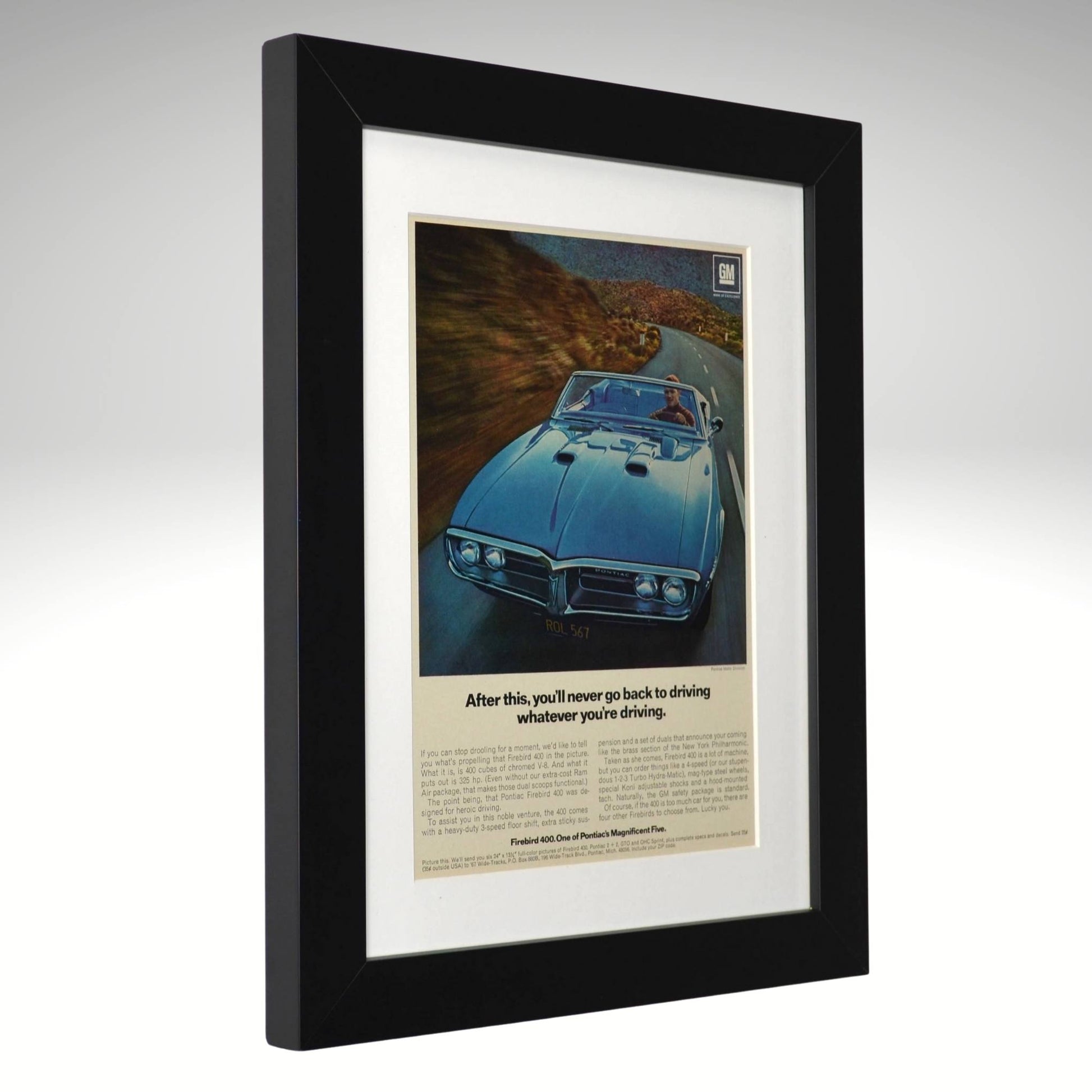Framed vintage advertisement of a 1967 pontaic firebird convertible  on a scenic road.