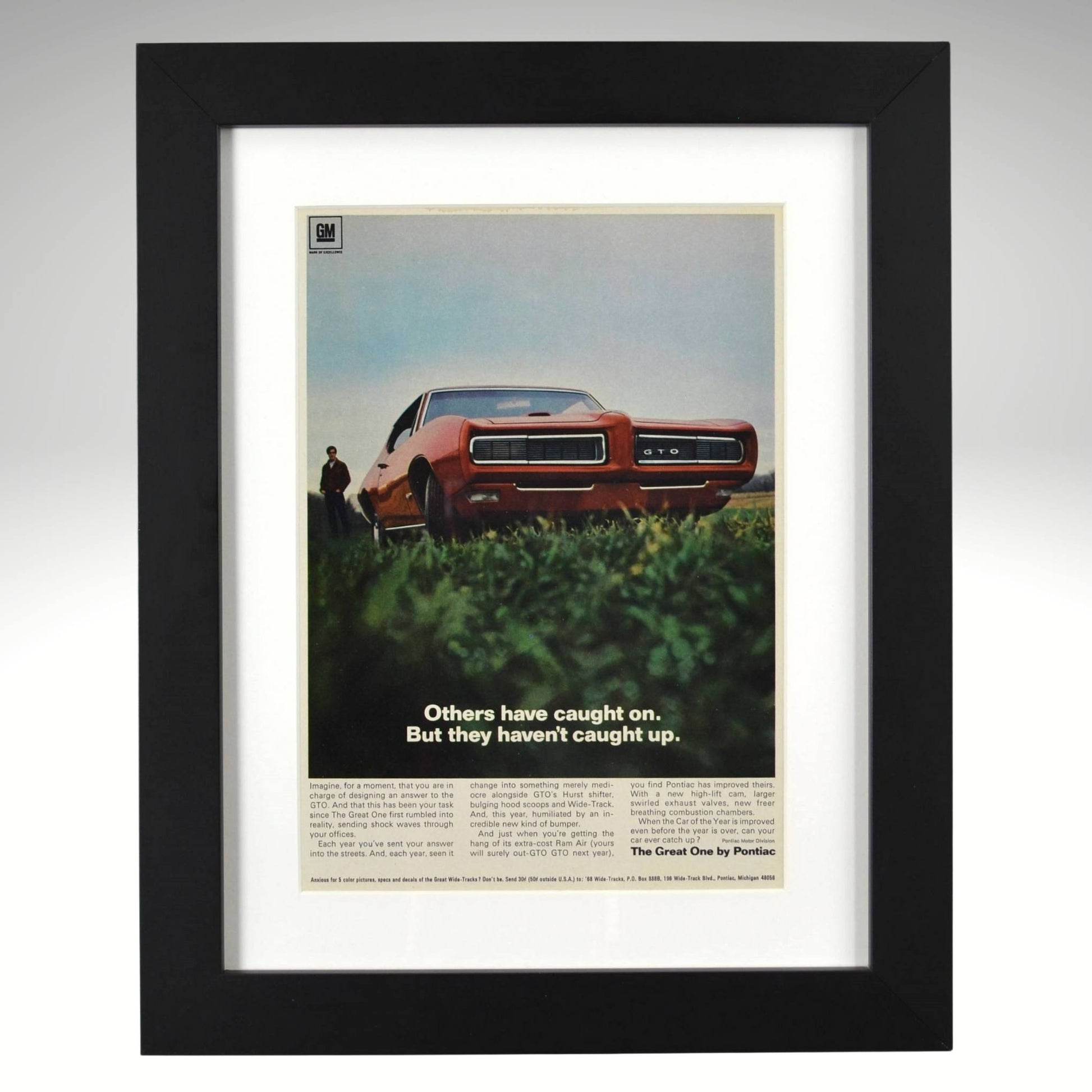 Framed 1968 Pontiac GTO print ad – vintage muscle car art featuring red GTO with hidden headlights and bold low-angle view.