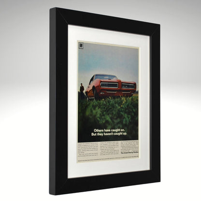 Framed 1968 Pontiac GTO print ad – vintage muscle car art featuring red GTO with hidden headlights and bold low-angle side view.