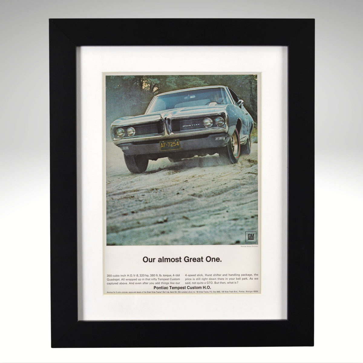 A framed vintage car advertisement print featuring a blue 1968 Pontiac tempest muscle car on a dirt road, with the headline 'Our almost Great One.' and smaller text below, shown in a black frame against a light gray background.