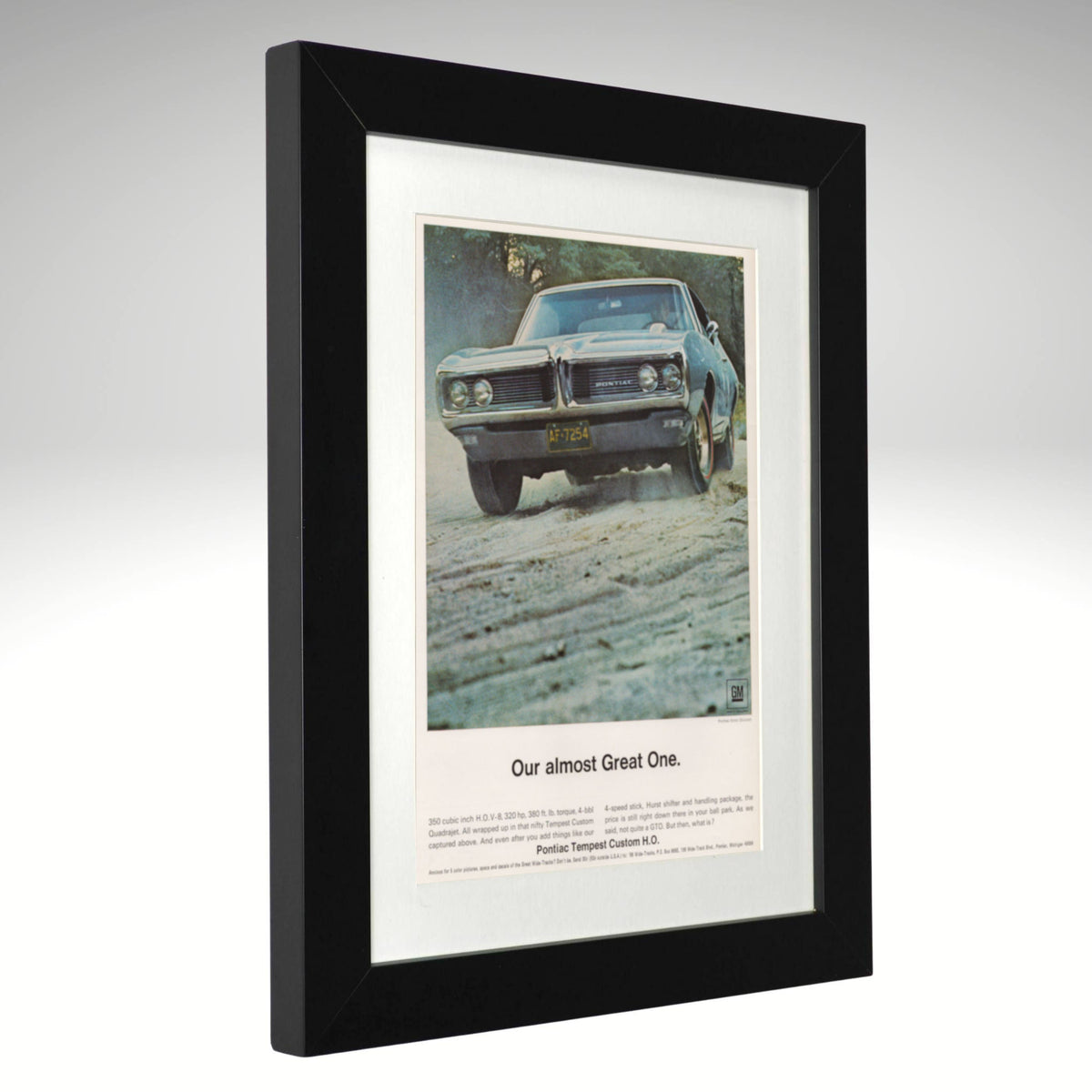 A framed vintage car advertisement print featuring a blue 1968 Pontiac tempest muscle car on a dirt road, with the headline 'Our almost Great One. angle view