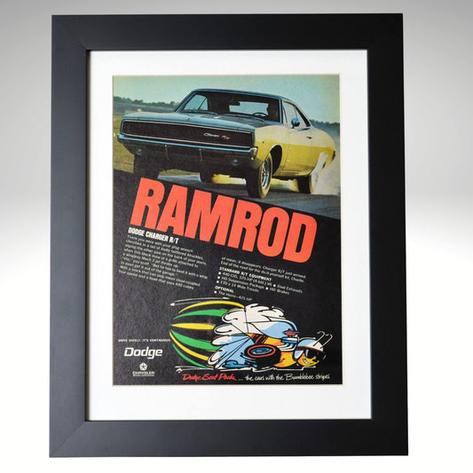 Framed 1969 Dodge Charger R/T “Ramrod” vintage print ad featuring a yellow Charger R/T launching hard with Scat Pack bumblebee logo and bold red lettering — authentic Mopar wall art for collectors.