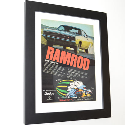 Framed 1969 Dodge Charger R/T “Ramrod” vintage print ad featuring a yellow Charger R/T launching hard with Scat Pack bumblebee logo and bold red lettering — authentic Mopar wall art for collectors side view