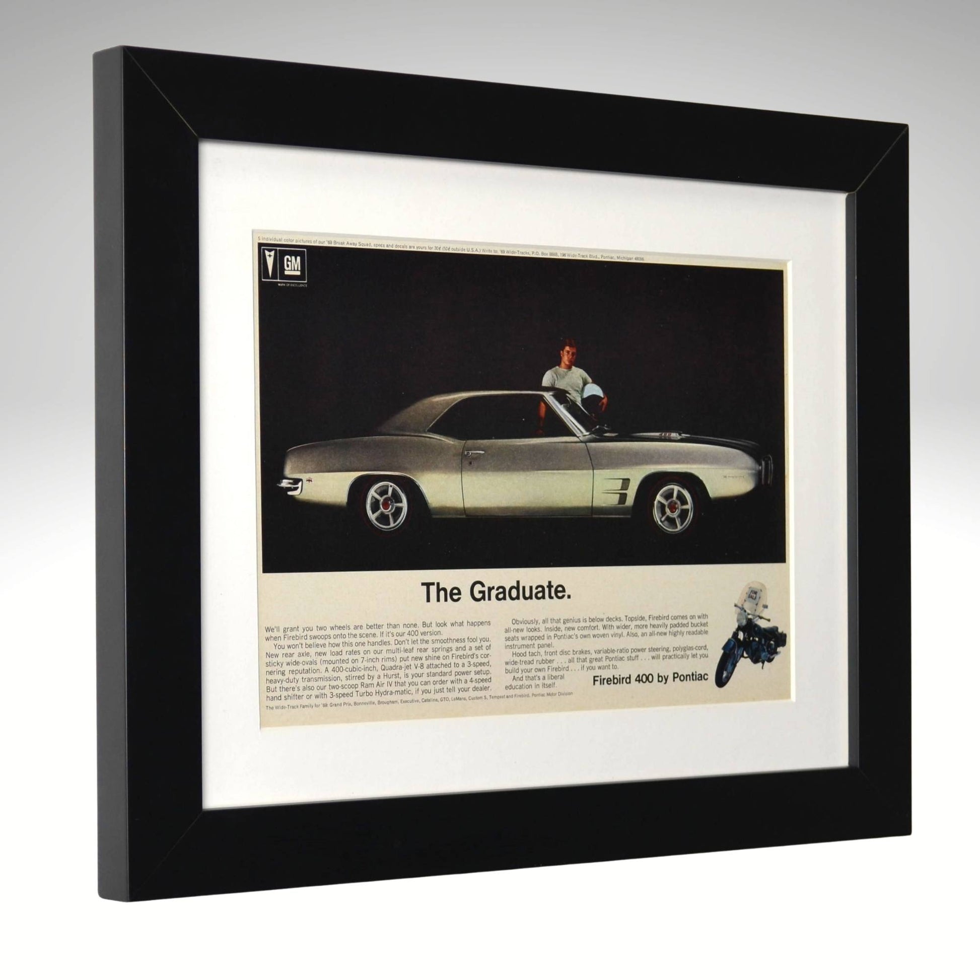 Framed advertisement for a 1969 Pontiac firebird featuring a person sitting on a car, with text 'The Graduate' 