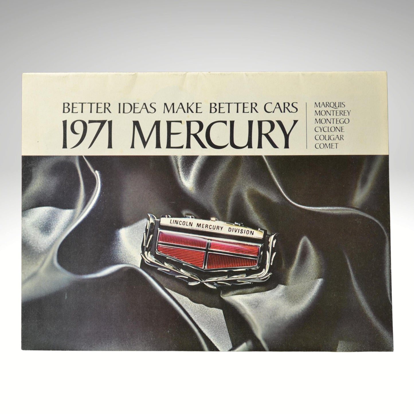 1971 Mercury car brochure cover with logo on a dark fabric background