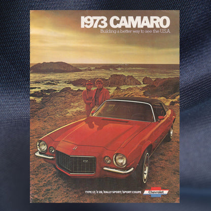 1973 Camaro advertisement with two people by a red car on a coastal landscape.