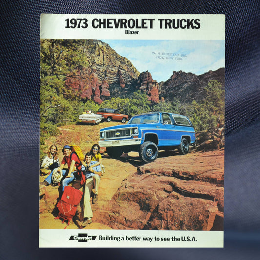 1973 Chevy Blazer dealer brochure cover featuring a blue Blazer on rugged red terrain with a group of hikers and a scenic mountain backdrop.