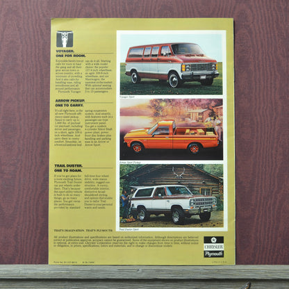 Vintage advertisement for Plymouth Voyager, Trail Duster, and Grand Voyager on a wooden surface.