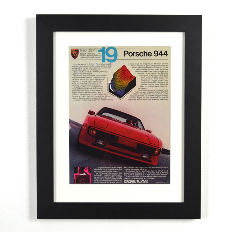 Framed vintage 1982 Porsche 944 magazine ad featuring red 944 in motion with technical graphics, dry-mounted and matted in black frame for wall display.