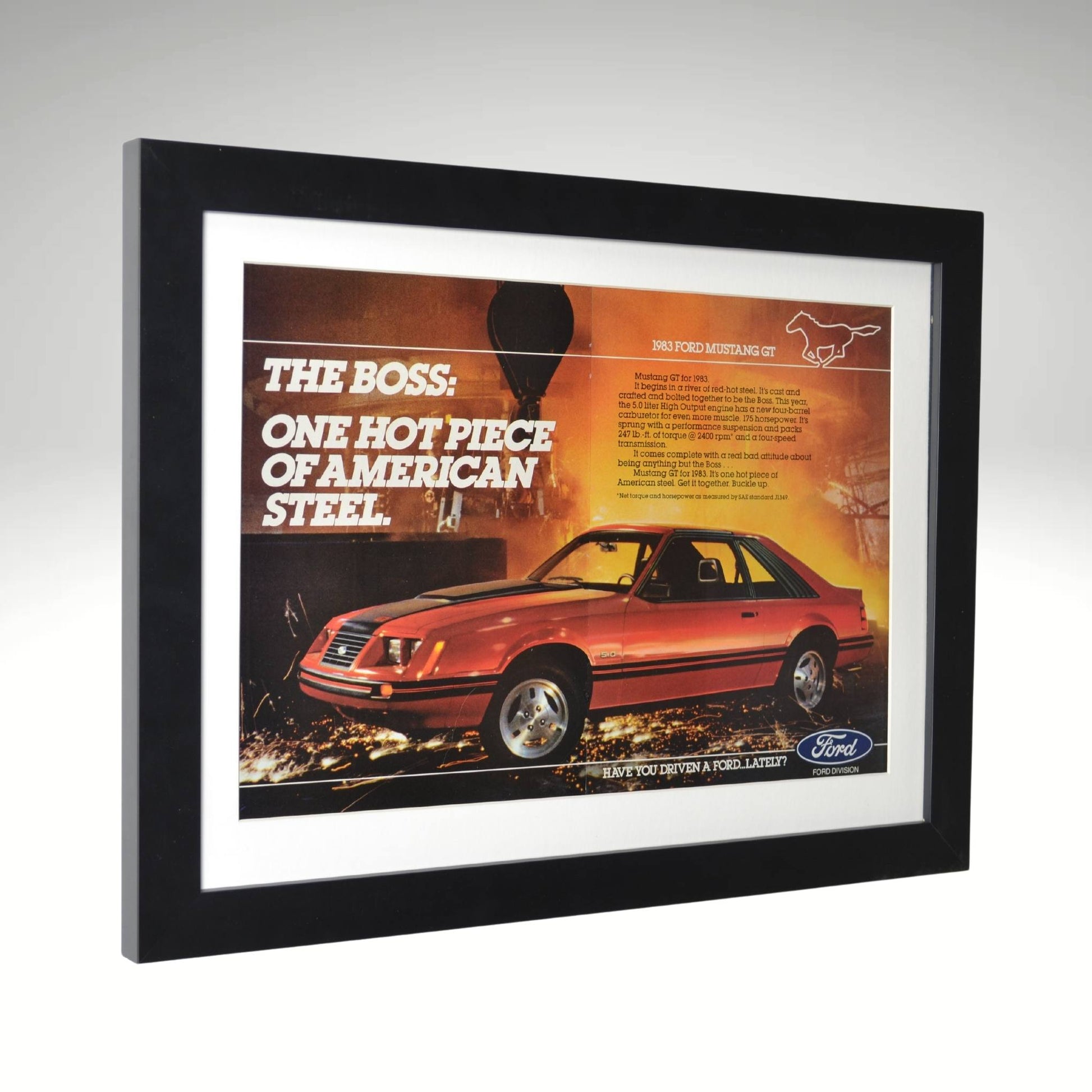 side view of red 1983 Ford Mustang GT framed print ad featuring the Fox Body design, 5.0L HO V8, and bold industrial backdrop.

