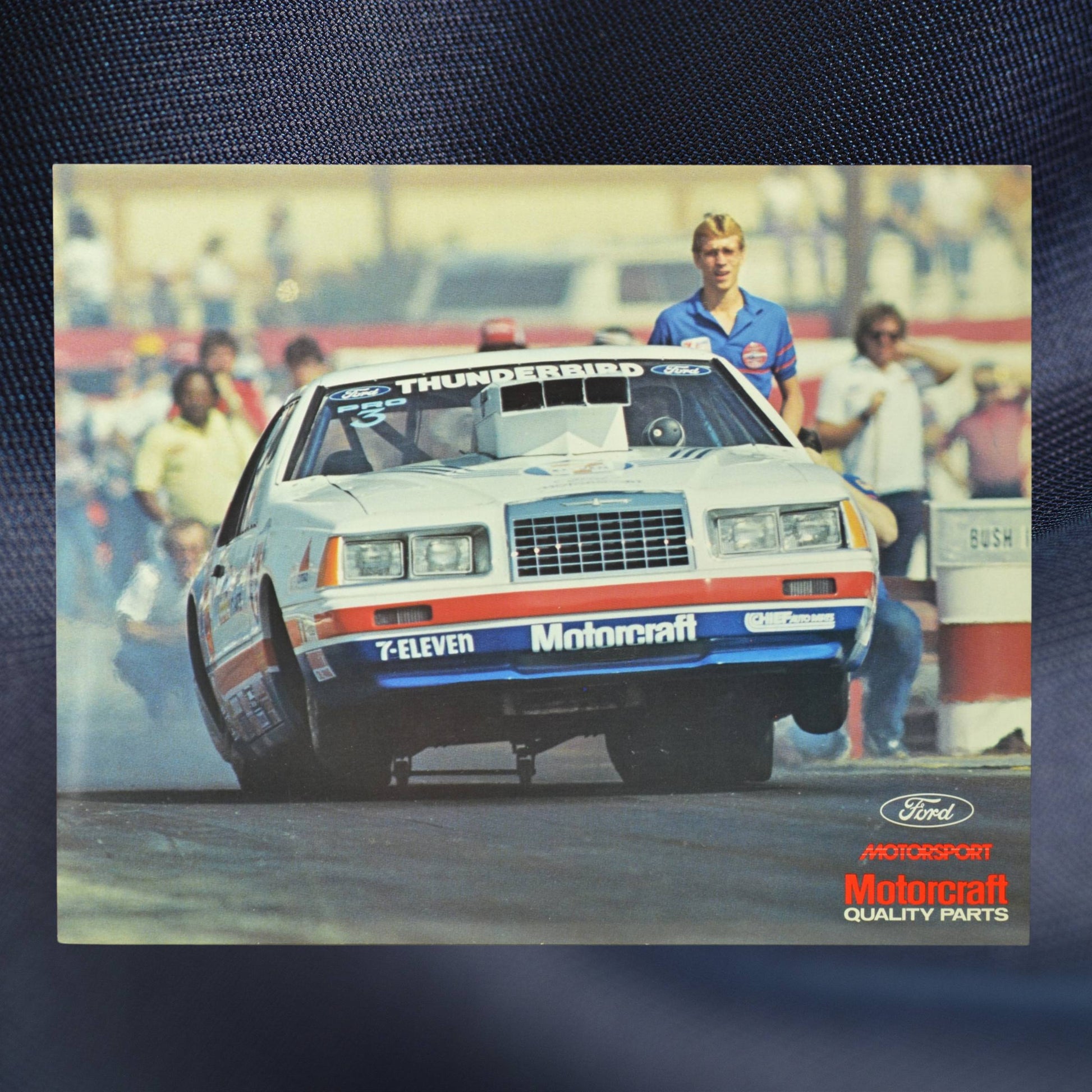 1984 NHRA hero card showing Bob Glidden’s Pro Stock Ford Thunderbird launching down the dragstrip, front wheels in the air, with a crowd in the background.