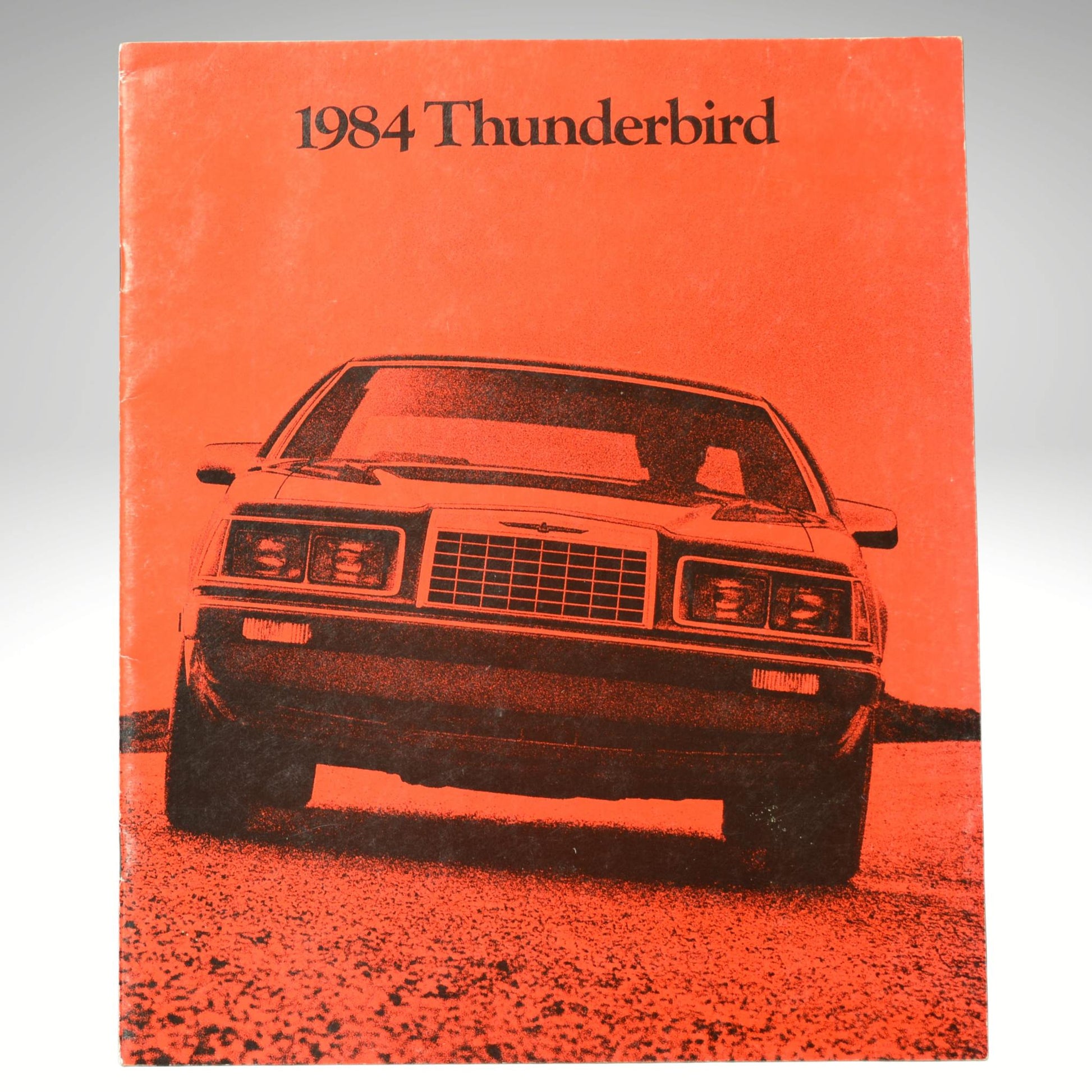1984 Thunderbird car sales brochure with an orange cover with black text