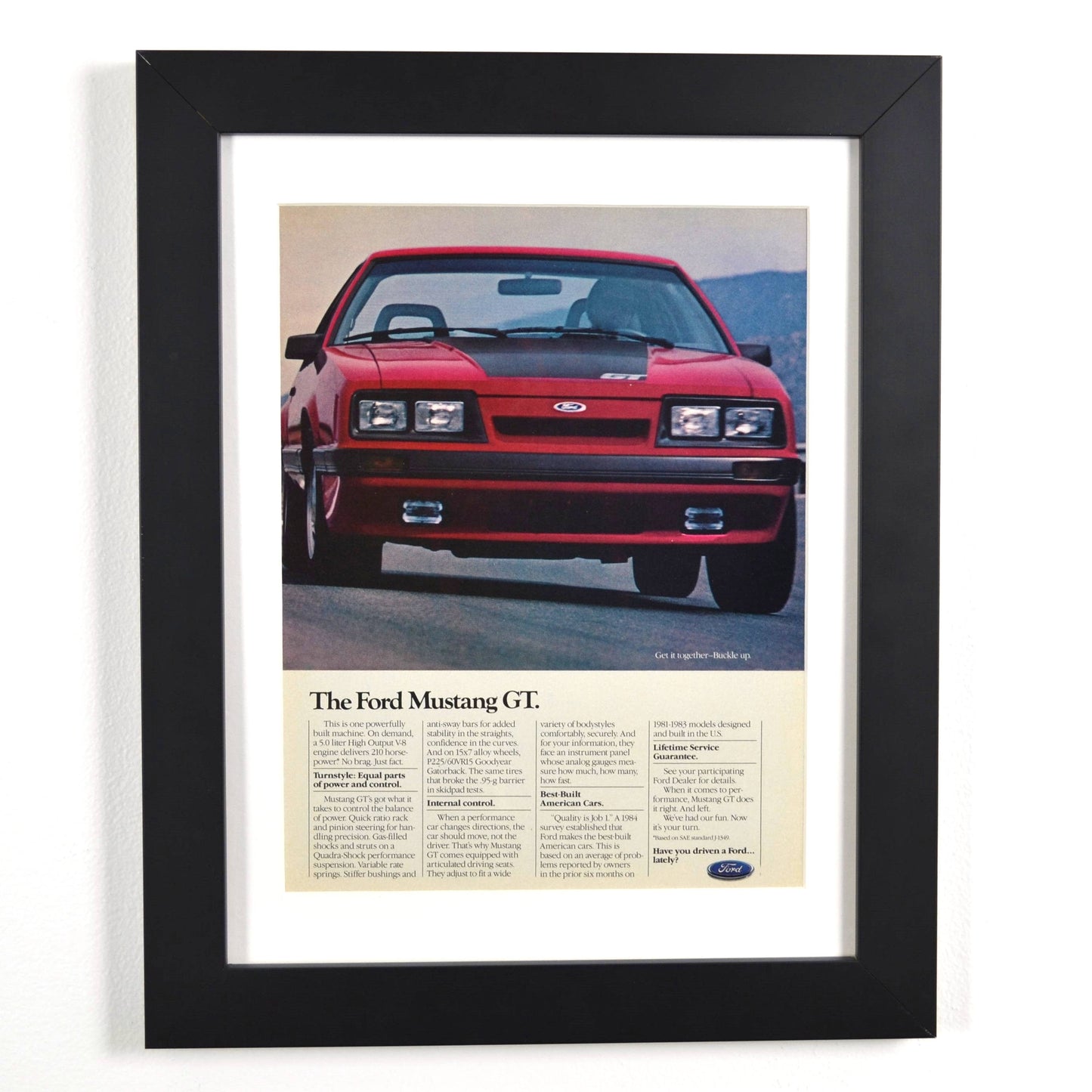 Framed 1985 Ford Mustang GT vintage print ad featuring the iconic Foxbody Mustang in red. Classic muscle car advertisement, perfect for garage decor and Mustang collectors.

