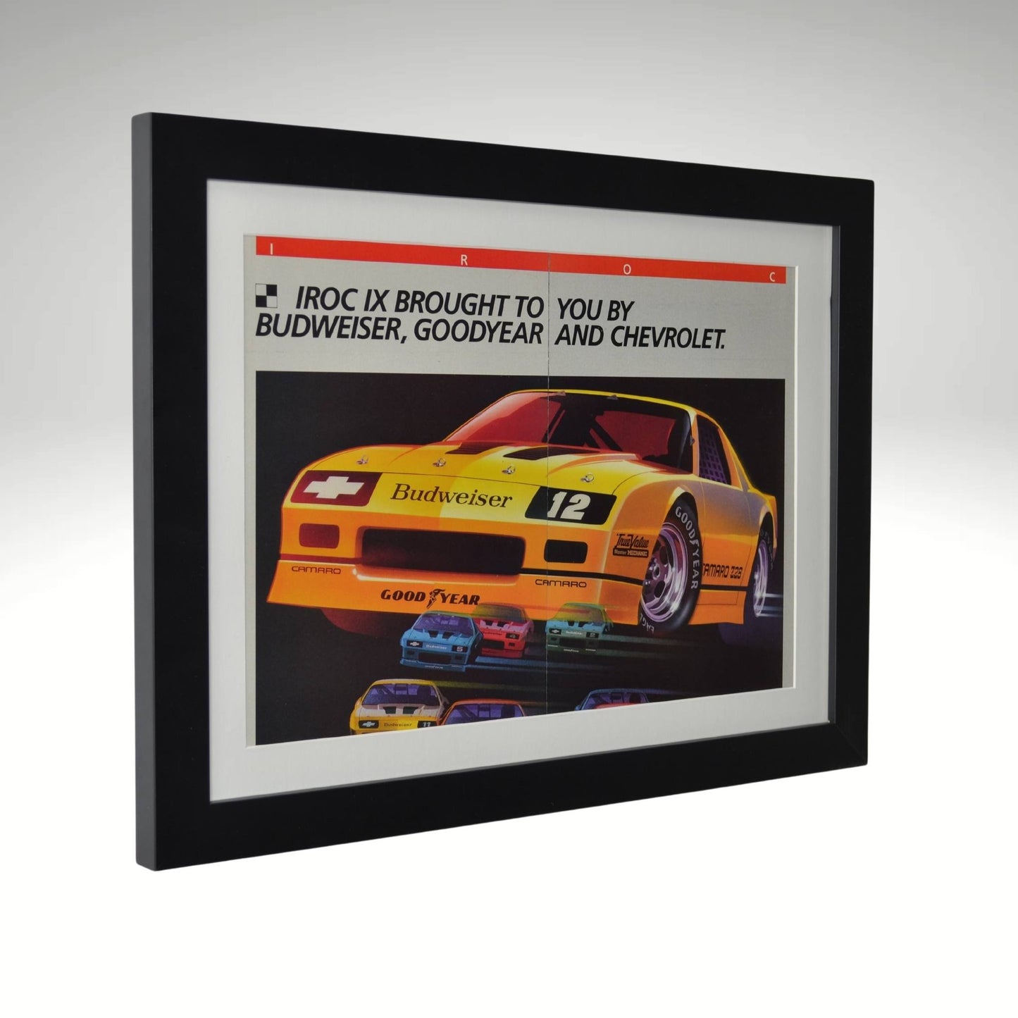 Side view of yellow 1986 Chevrolet IROC Camaro framed vintage print ad featuring the Budweiser-sponsored Z28 race car, Goodyear branding, and bold racing graphics.