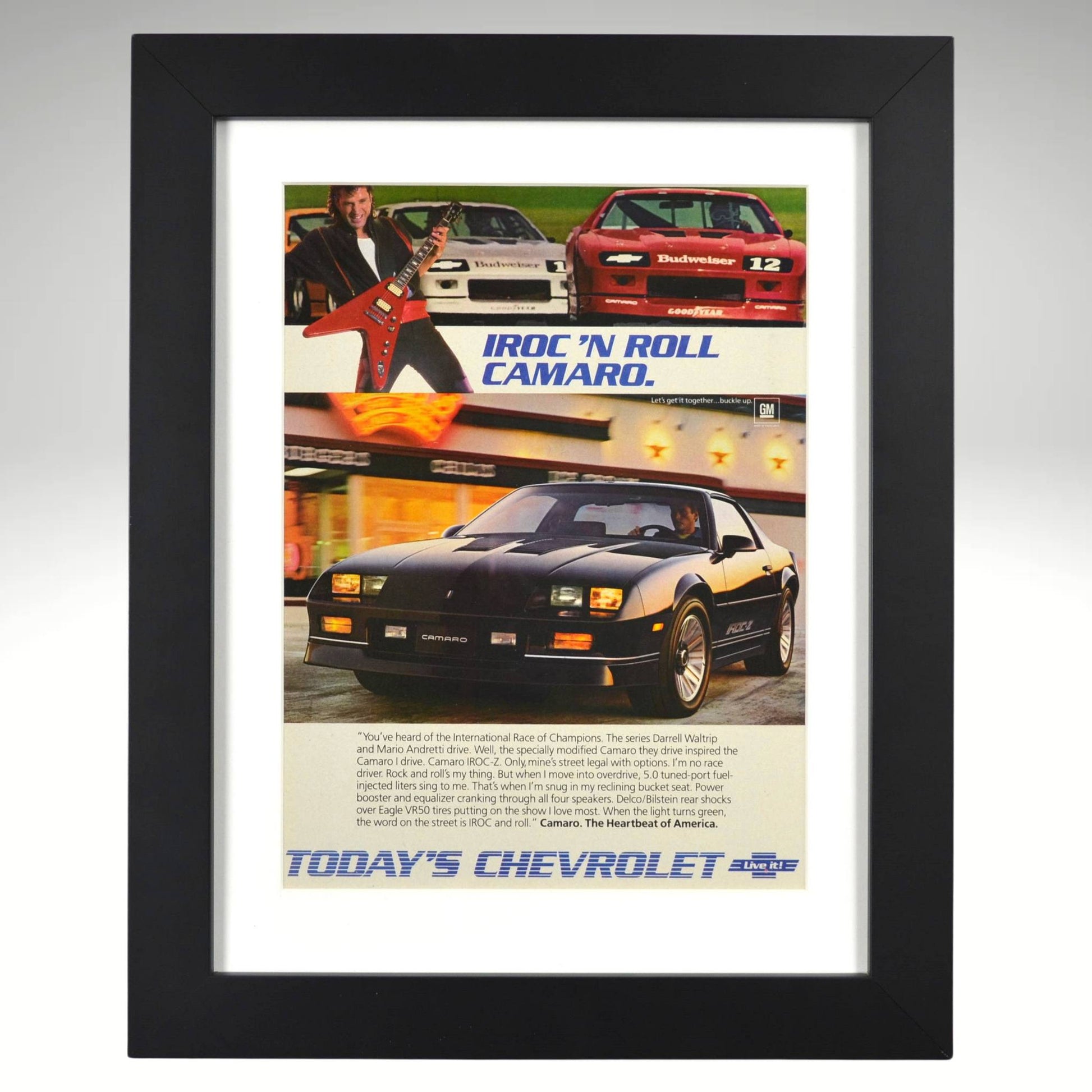 Framed 1986 Chevy Camaro IROC-Z print ad – black IROC with race cars, guitars, and “IROC ’N ROLL” headline.