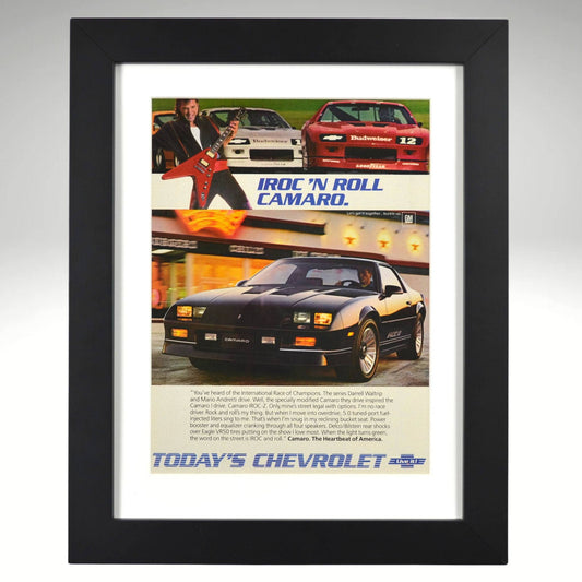 Framed 1986 Chevy Camaro IROC-Z print ad – black IROC with race cars, guitars, and “IROC ’N ROLL” headline.