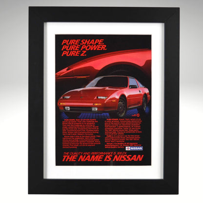 Framed 1987 Nissan 300ZX vintage print ad featuring a red 300ZX with bold headline “Pure Shape. Pure Power. Pure Z.” Displayed in a matte black frame with white mat — perfect retro automotive wall art for collectors.