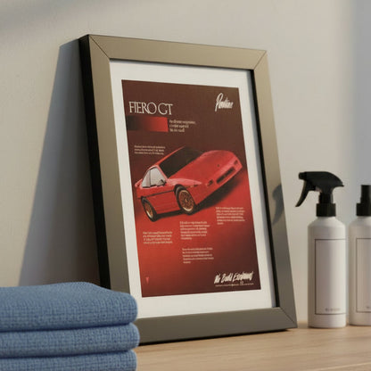 A framed vintage 1988 pontiac Fiero GT car advertisement print, featuring a red sports car on a dark red background with white matting and a black frame, shown at a three-quarter angle against a light gray gradient background.