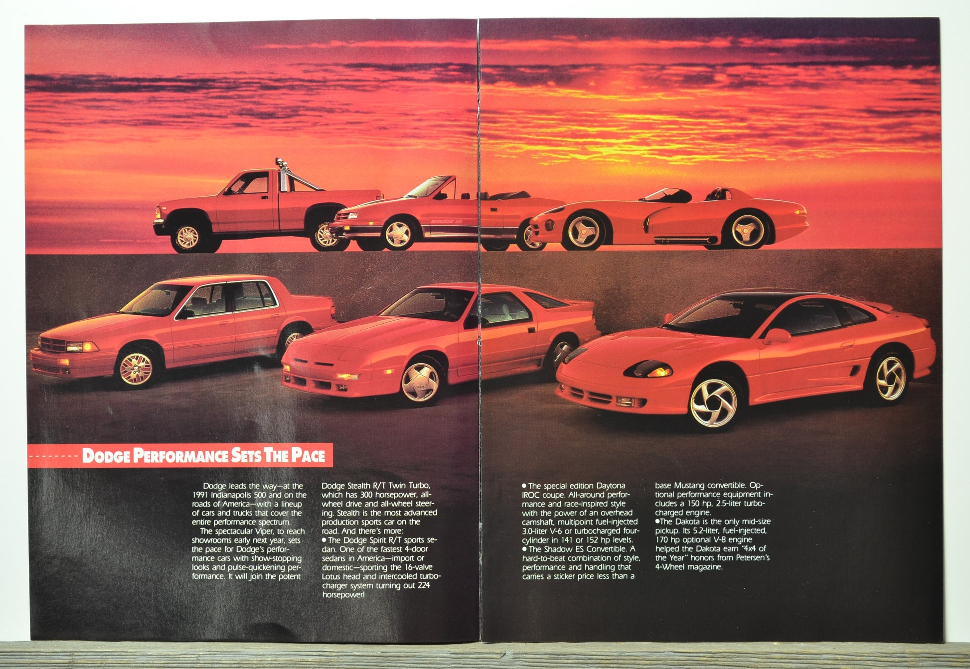 Brochure page with images of red Dodge sports cars against a sunset sky.
