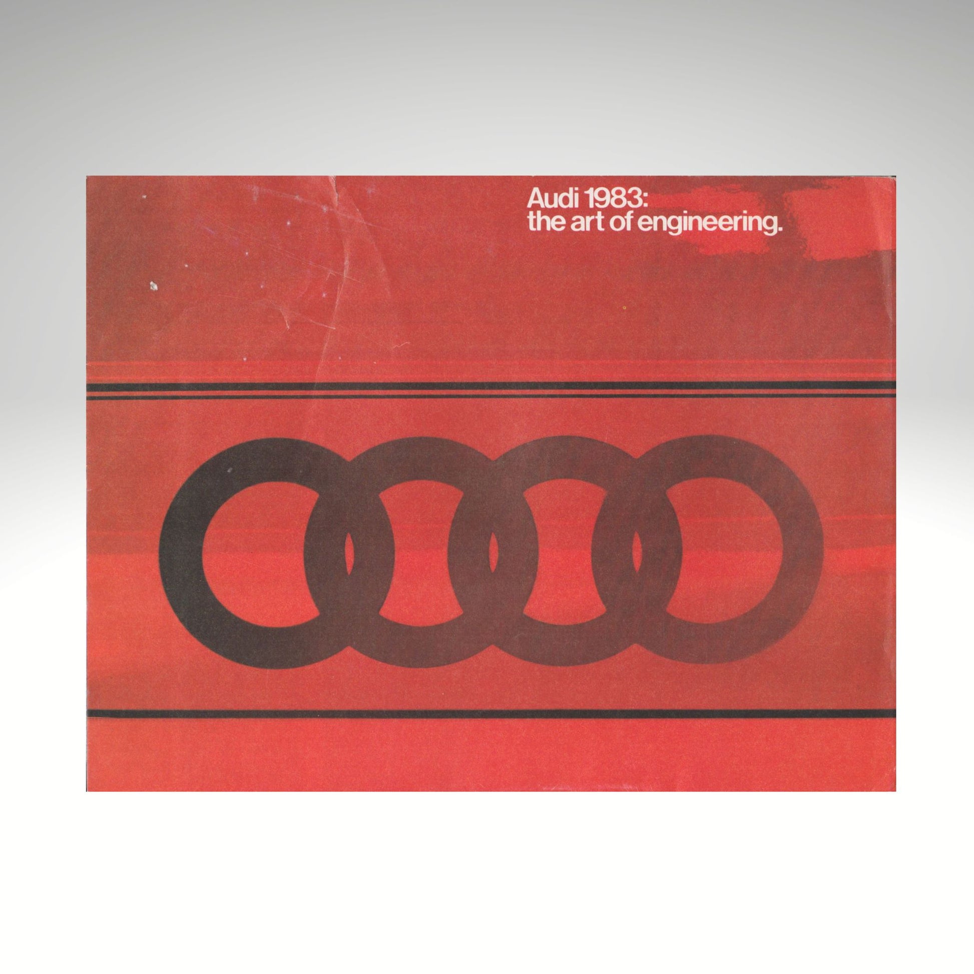 Audi logo on a red background with text 'Audi 1983: the art of engineering' on a gray background