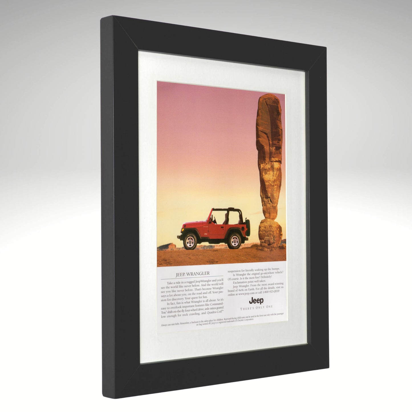 Framed advertisement of a Jeep Wrangler in a desert landscape with a rock formation.