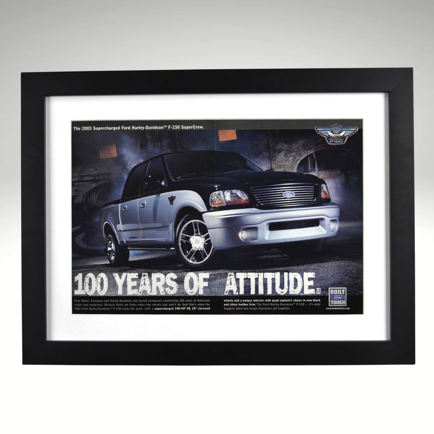 Framed vintage 2003 Ford Harley-Davidson F-150 print ad featuring a black and silver SuperCrew pickup with Harley-Davidson badging. Professionally dry mounted and displayed in a 15x20 matte black frame with white matting.1