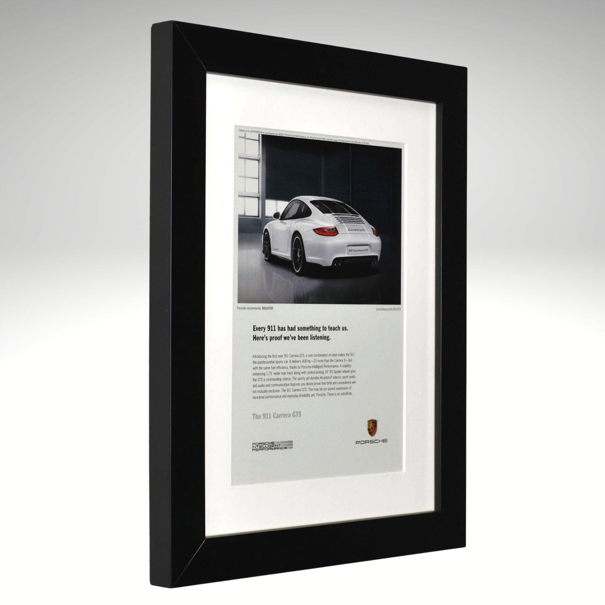 Framed advertisement of a white Porsche 911 GTS car on a gray background