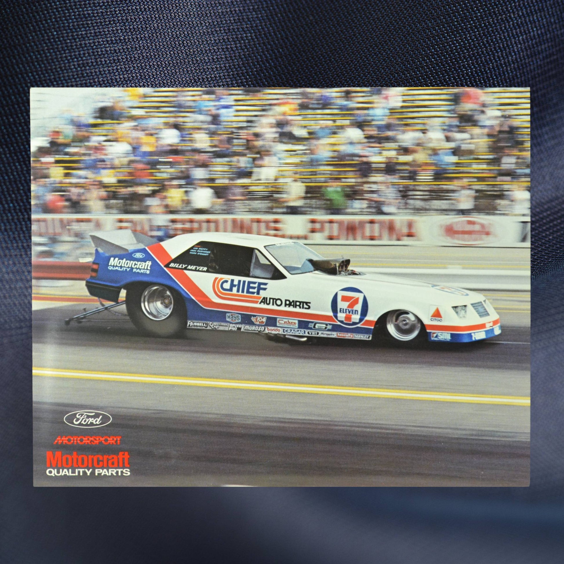 1984 NHRA hero card showing Billy Meyer’s 7-Eleven/Chief Auto Parts Mustang Funny Car speeding down the track at Pomona with a blurred crowd in the background.