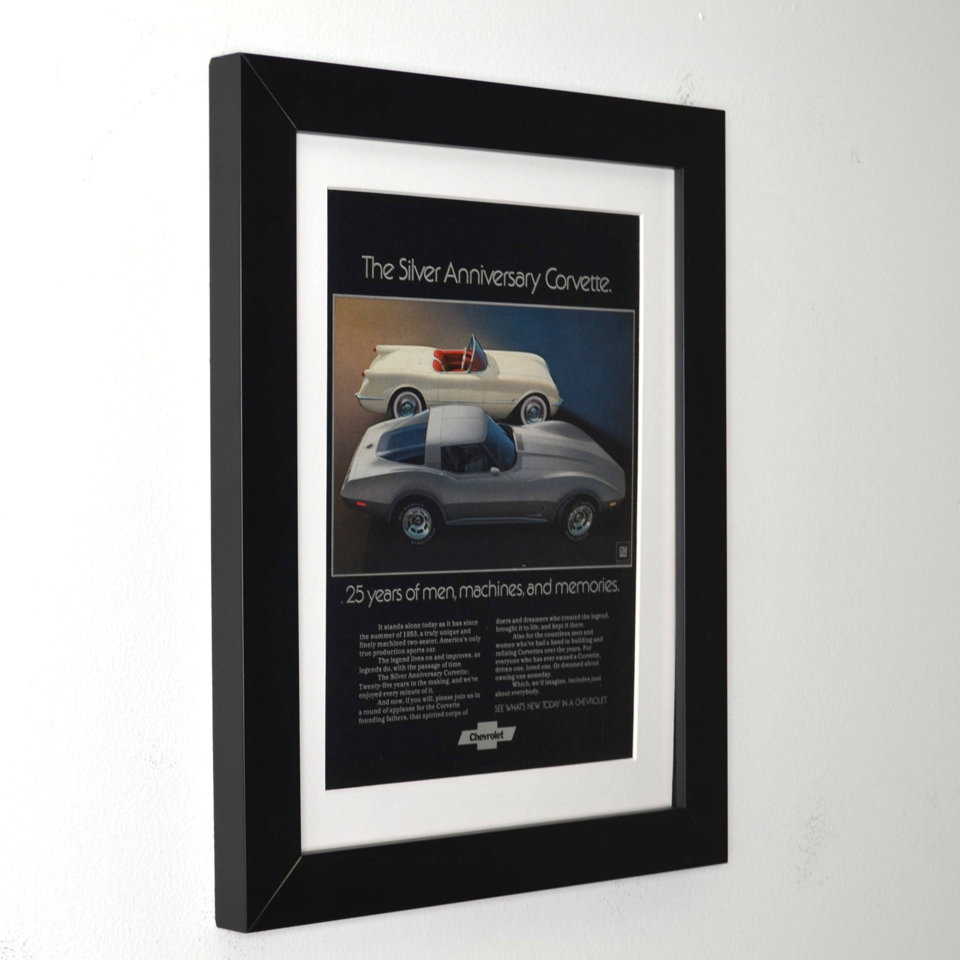 Framed poster of a Silver Anniversary  1953 and 1978 Corvette on a white wall