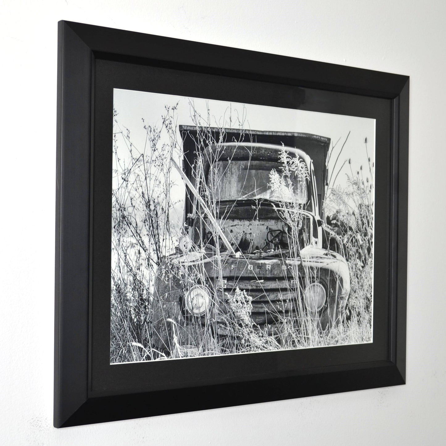 Framed black and white photograph of a vintage ford truck in a field