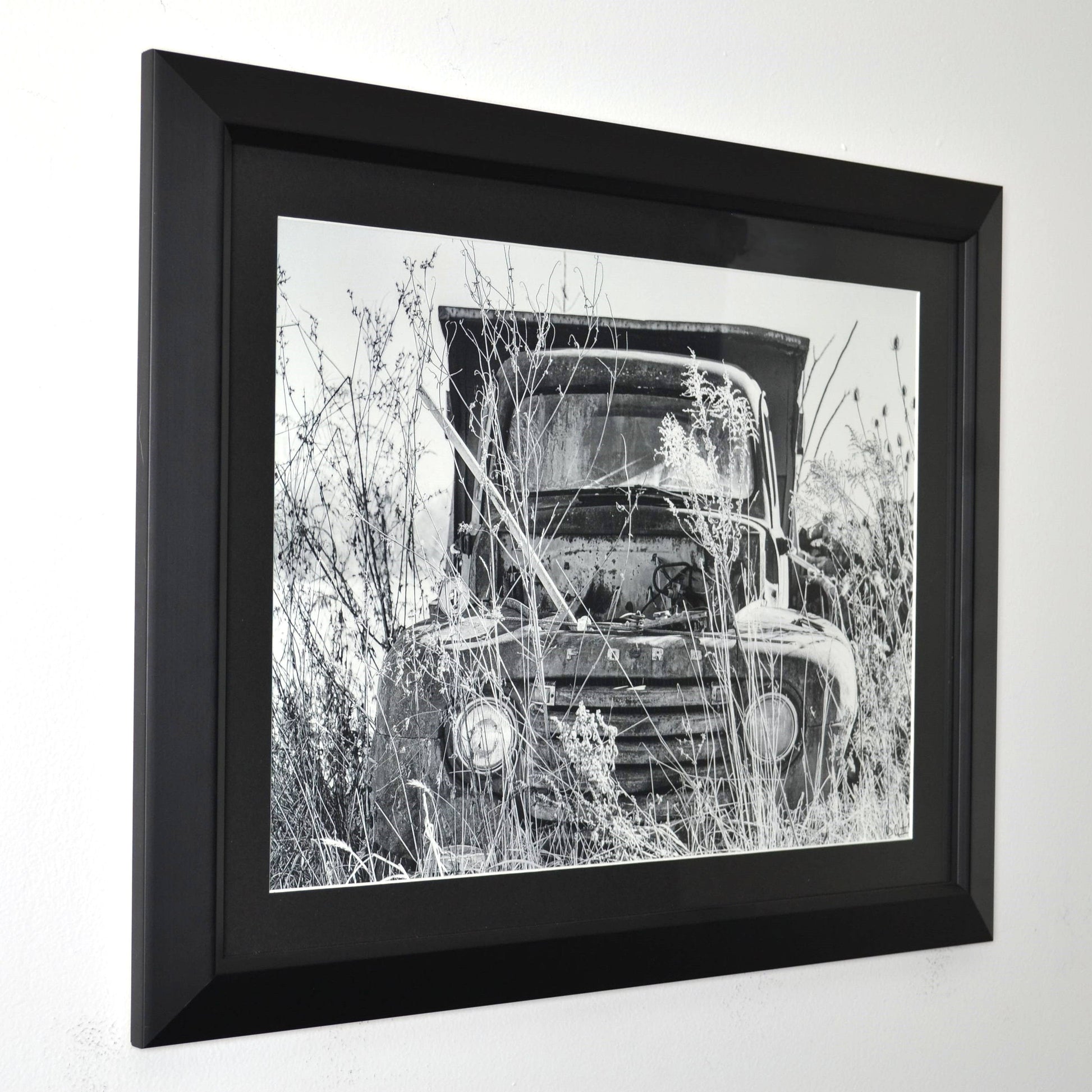 Framed black and white photograph of a vintage ford truck in a field